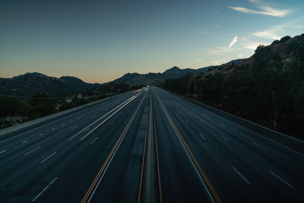 pexels-photo-12421058-12421058 A serene aerial view of an empty mountainous highway at dusk, showing the vastness and tranquility.