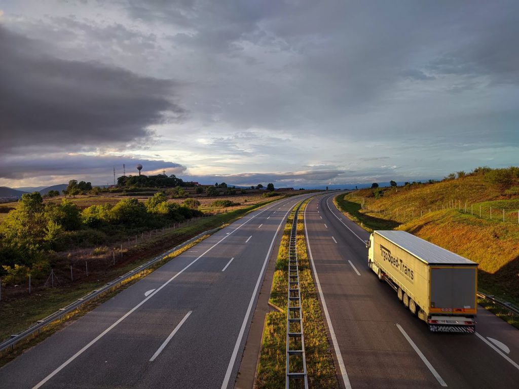 pexels-photo-13682891 A scenic highway under a dramatic cloudy sky with a lone truck driving on an open road.